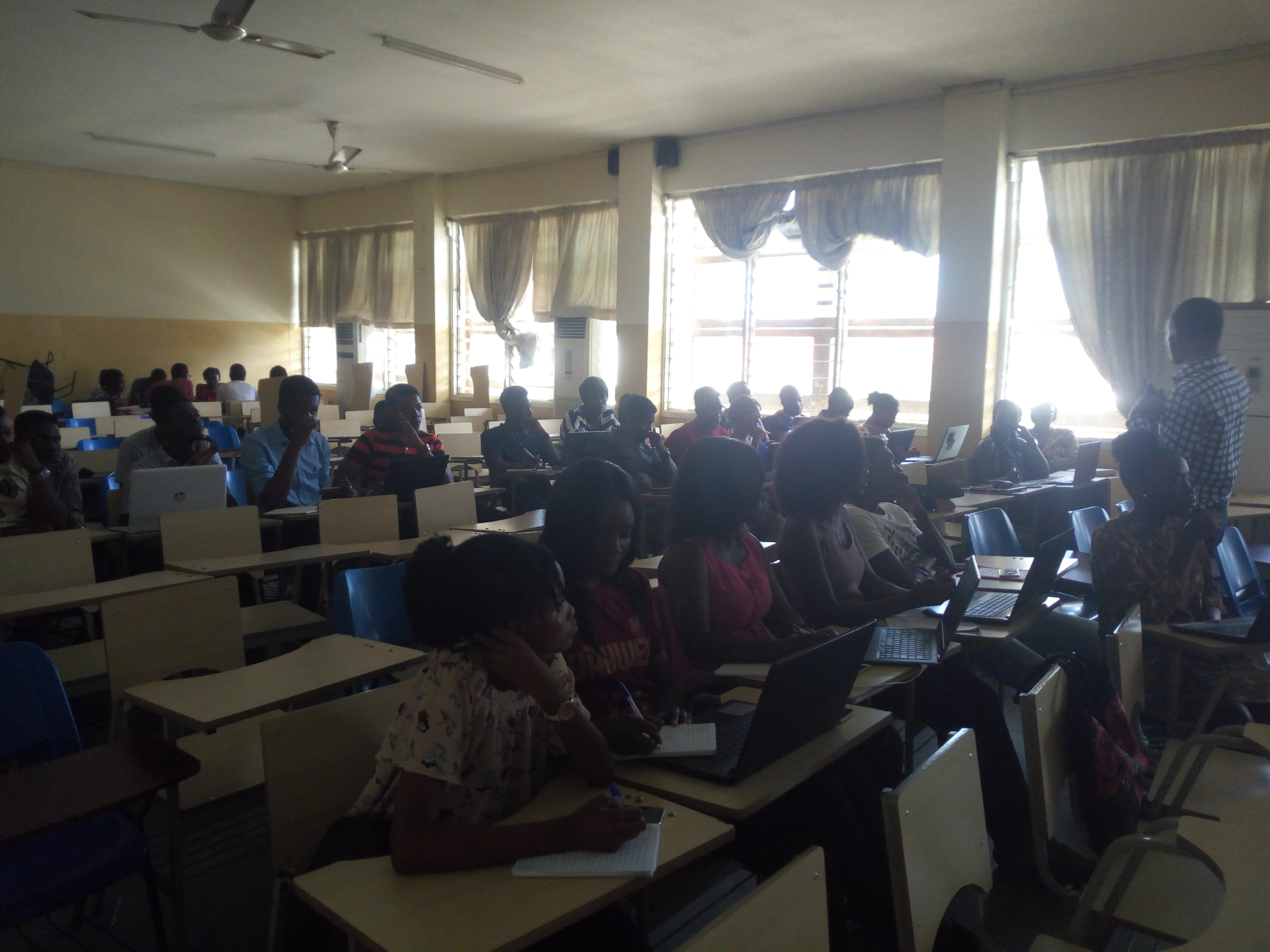Cohort of African students learning on laptops in a sunlit lecture hall