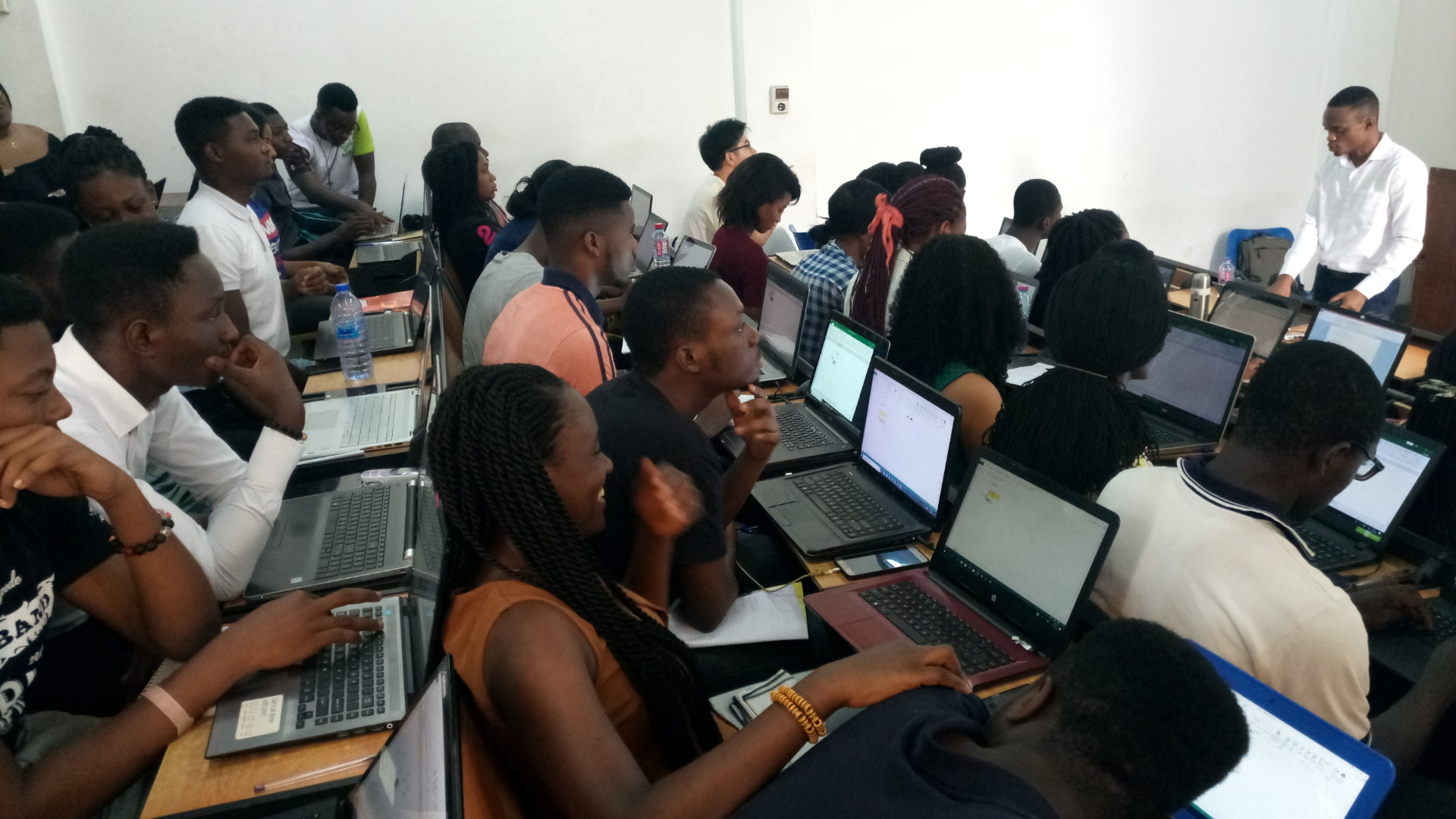 A packed computer lab of students working on laptops during a Finex training